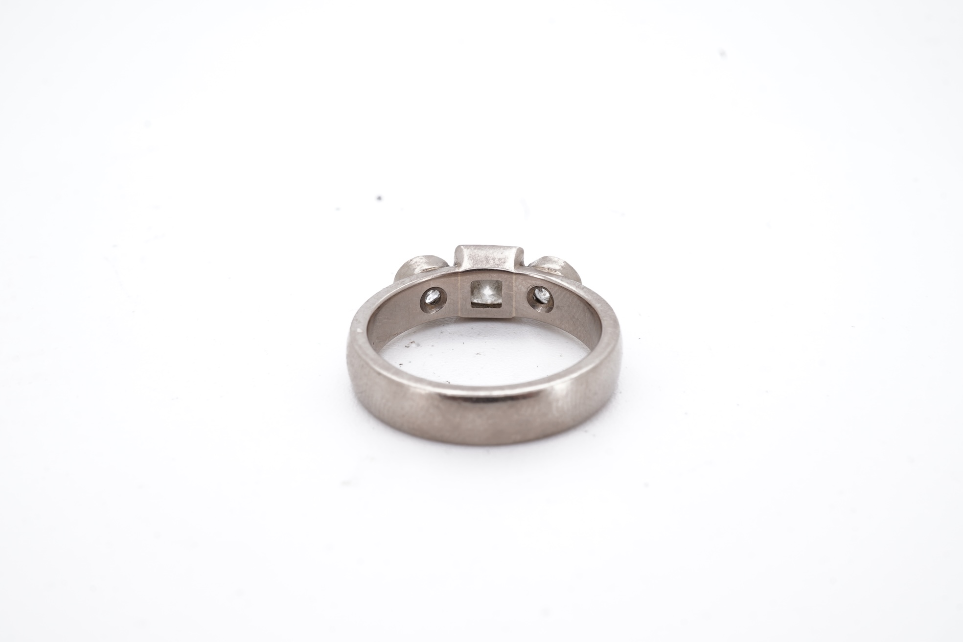 A modern 18ct white gold and three stone diamond ring, set with single square cut diamond and two round cut diamonds, size K, gross weight 5.8 grams.